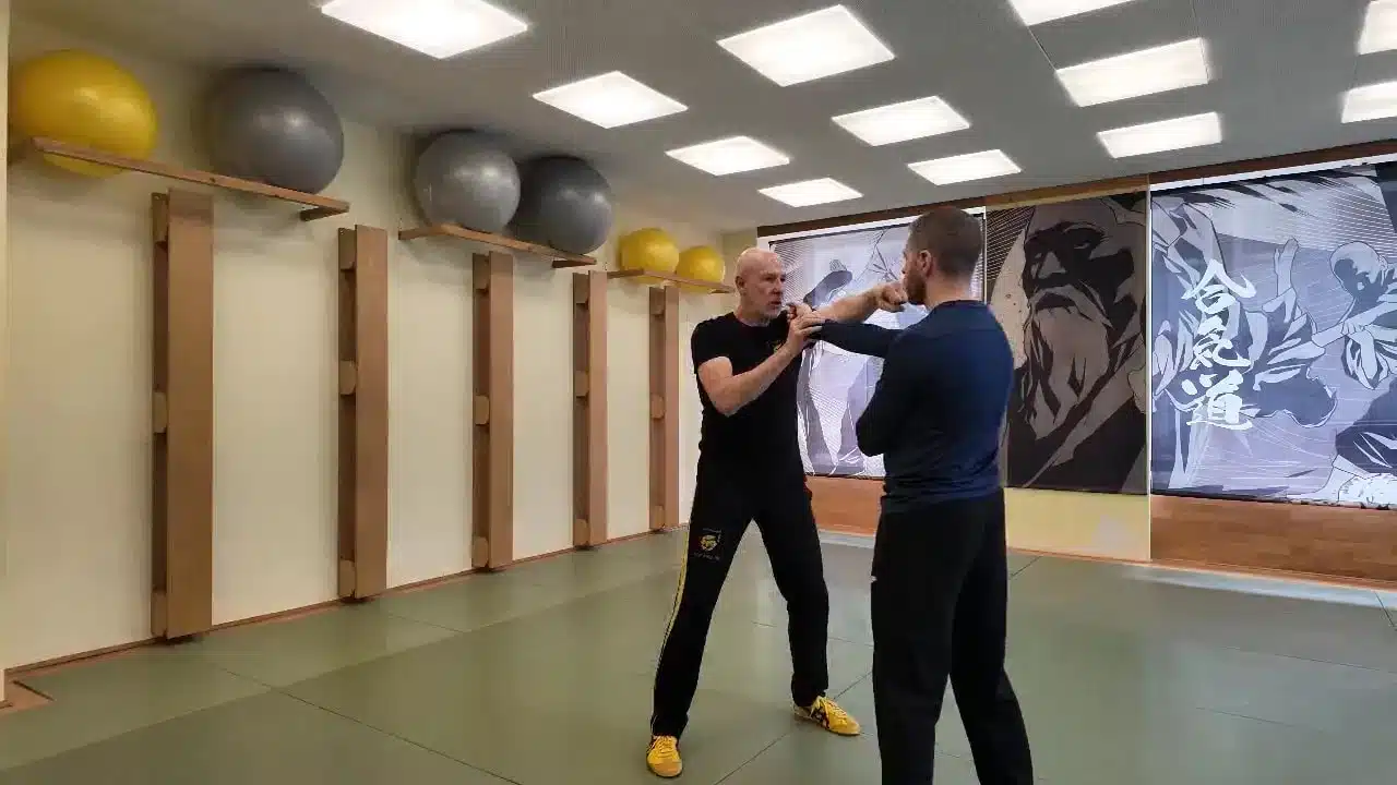 Zwei Trainingspartner im Dojo mit ausgestreckten Armen und Kontakt auf Oberkörperhöhe